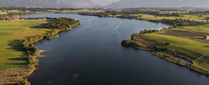 Vogelperspektive auf die Uferlandschaft des Riegsees mit angrenzenden Feldern und Grundstücken