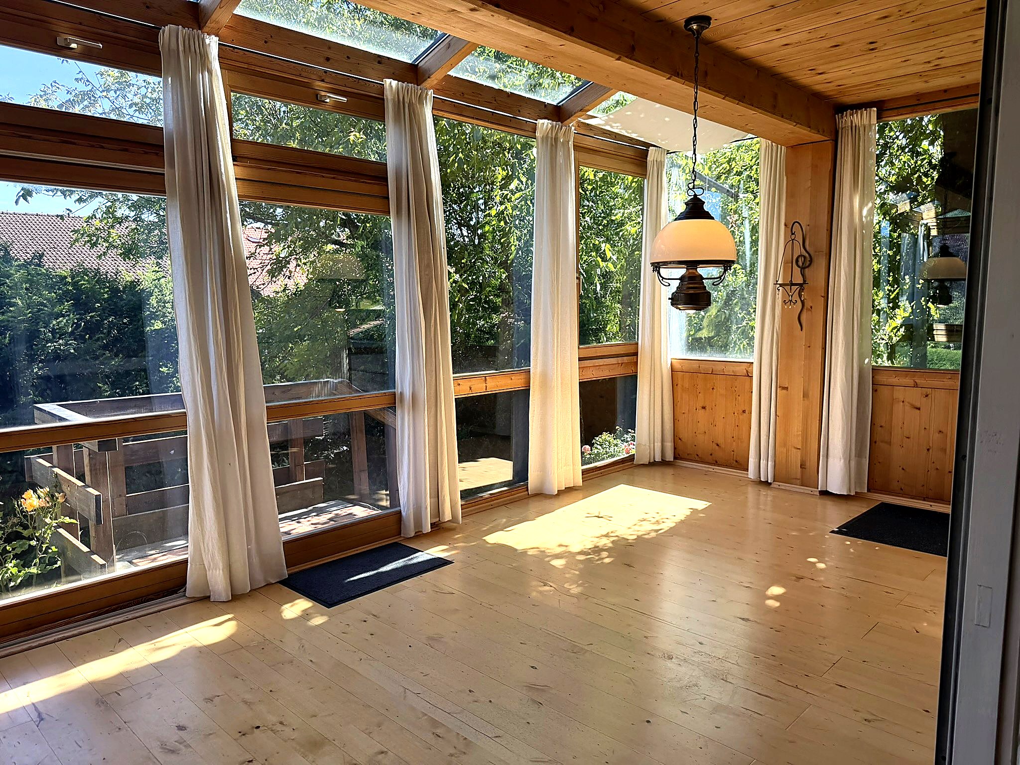Heller Wohnraum mit Fensterfront und Holzdecke in einem oberbayerischen Haus